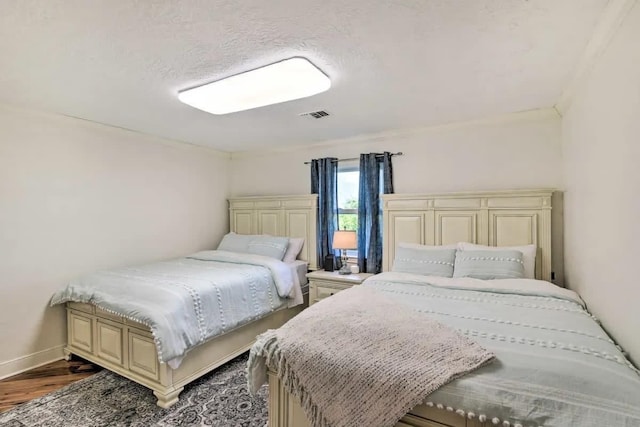 bedroom featuring visible vents, baseboards, and wood finished floors