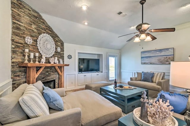 living room featuring vaulted ceiling, ceiling fan, a wainscoted wall, and visible vents