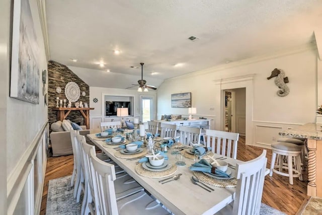 dining area with vaulted ceiling, wainscoting, wood finished floors, and visible vents