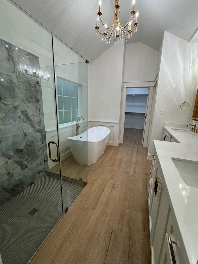 bathroom featuring an inviting chandelier, hardwood / wood-style floors, vanity, vaulted ceiling, and shower with separate bathtub