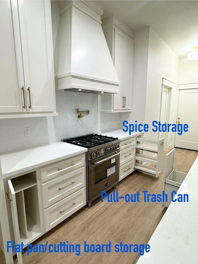 kitchen featuring white cabinetry, stainless steel range, wood-type flooring, and custom range hood