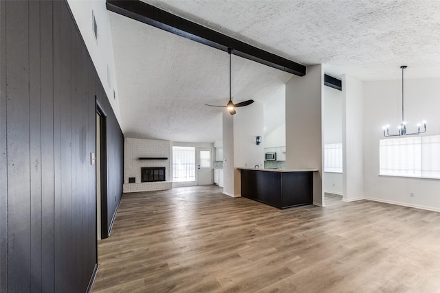 15038 Timberlea Dr, Houston, TX 77489 - unfurnished living room with a chandelier, a brick fireplace, a textured ceiling, high vaulted ceiling, and wood walls