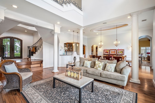 living room featuring ornamental molding, an inviting chandelier, decorative columns, and hardwood / wood-style flooring