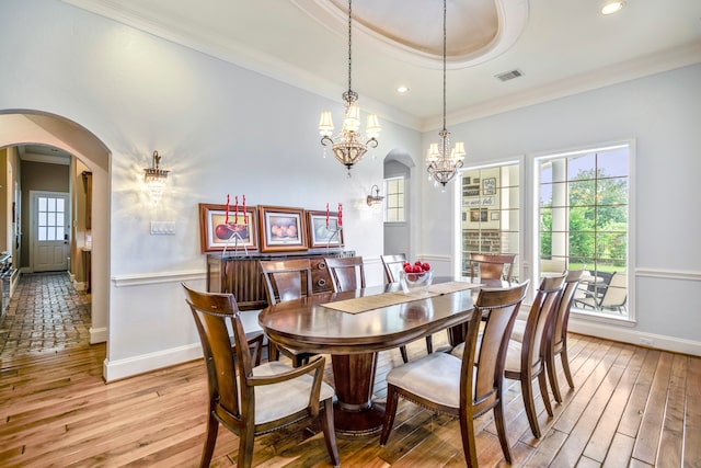 dining room featuring a notable chandelier, light hardwood / wood-style flooring, crown molding, and a tray ceiling