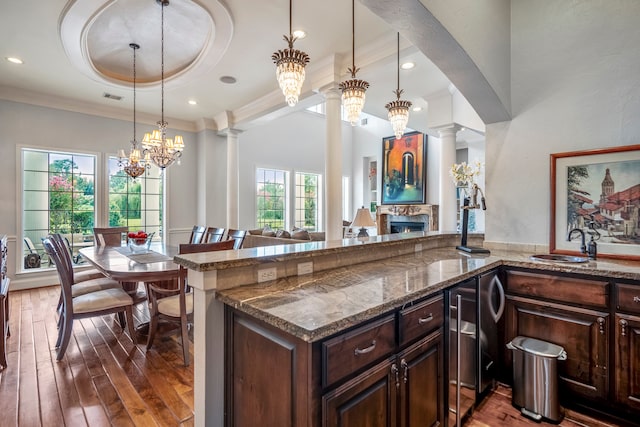 kitchen featuring a notable chandelier, a wealth of natural light, dark hardwood / wood-style floors, and ornate columns