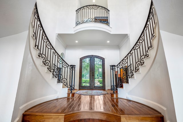 entrance foyer featuring crown molding, a towering ceiling, french doors, and hardwood / wood-style flooring