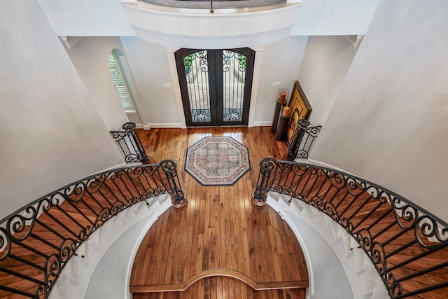 entryway featuring french doors, a towering ceiling, and hardwood / wood-style floors