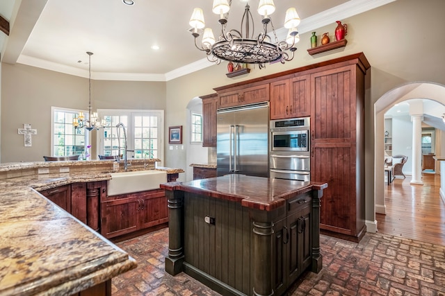 kitchen featuring light stone countertops, stainless steel appliances, an inviting chandelier, decorative light fixtures, and sink