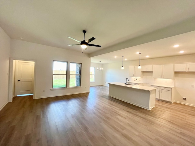 726 Blue Stone Dr, Beasley, TX 77417 - kitchen featuring wood finished floors, a ceiling fan, a kitchen island with sink, white cabinetry, and a chandelier