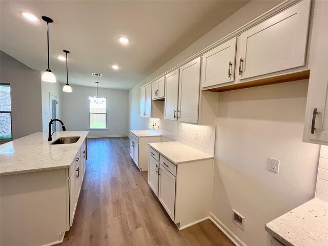 726 Blue Stone Dr, Beasley, TX 77417 - kitchen featuring light wood-type flooring, light stone countertops, an island with sink, and recessed lighting