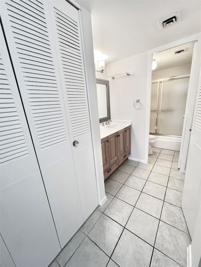 full bathroom featuring vanity, toilet, combined bath / shower with glass door, and tile patterned flooring