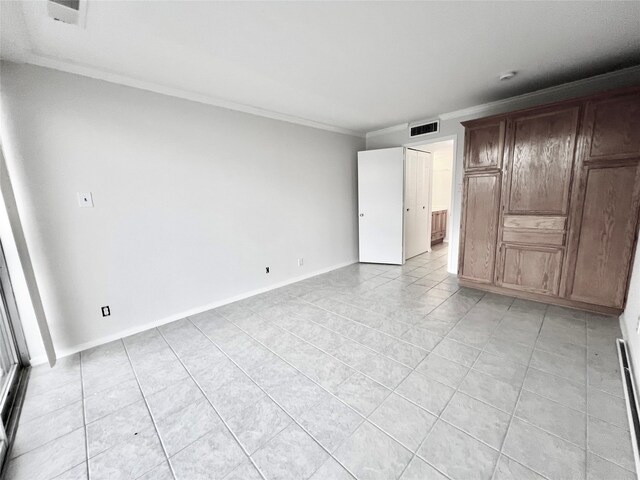 spare room featuring crown molding and light tile patterned floors