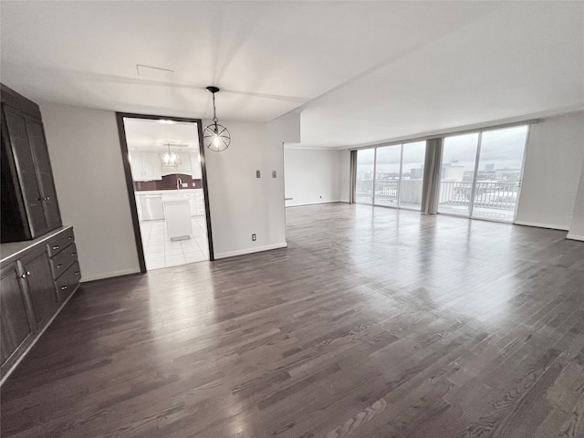 unfurnished living room with dark hardwood / wood-style floors, a chandelier, and floor to ceiling windows