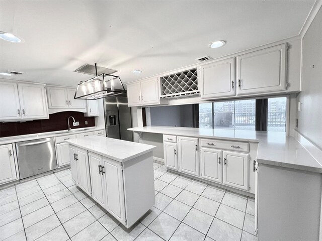 kitchen featuring light tile patterned flooring, a center island, white cabinetry, stainless steel appliances, and decorative light fixtures