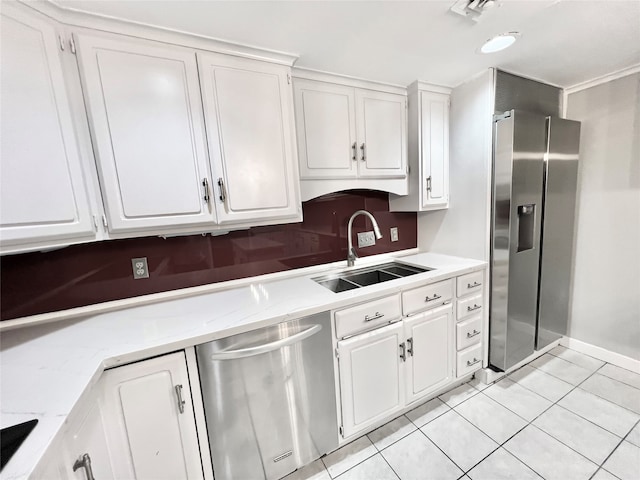 kitchen with stainless steel appliances, sink, light tile patterned floors, white cabinetry, and light stone counters