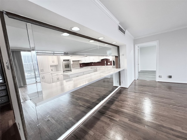 kitchen featuring kitchen peninsula, white cabinets, stainless steel oven, dark wood-type flooring, and pendant lighting