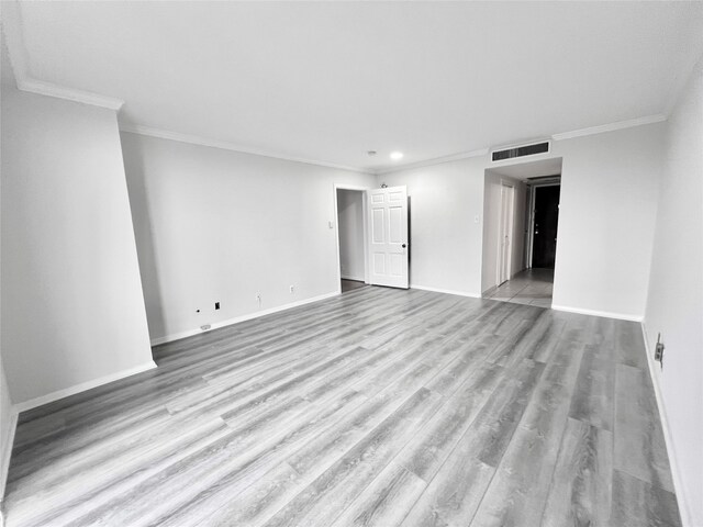 empty room with ornamental molding and light hardwood / wood-style floors