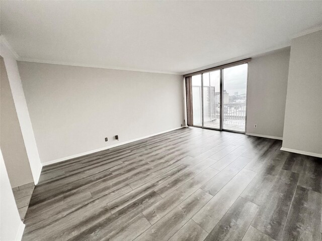 empty room featuring ornamental molding, dark hardwood / wood-style flooring, and a wall of windows