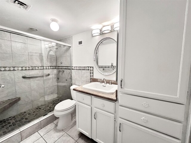 bathroom featuring toilet, an enclosed shower, vanity, and tile patterned floors