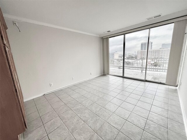 tiled spare room featuring crown molding and a wall of windows