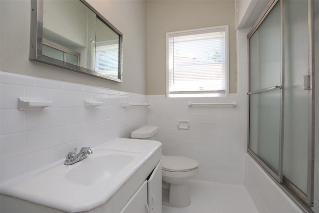 full bathroom featuring tasteful backsplash, tile walls, bath / shower combo with glass door, toilet, and vanity