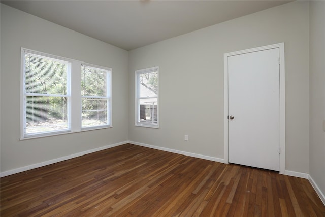 empty room featuring a healthy amount of sunlight and dark hardwood / wood-style flooring