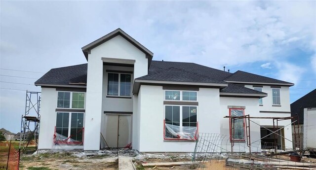 back of property with roof with shingles and stucco siding