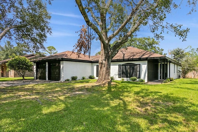 rear view of house featuring a garage, brick siding, and a lawn