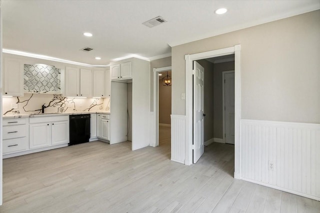 kitchen with black dishwasher, light countertops, light wood-style flooring, and visible vents