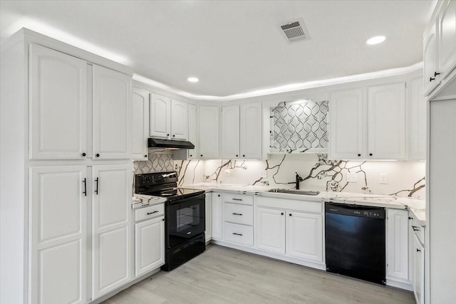 kitchen featuring visible vents, light wood-style flooring, under cabinet range hood, black appliances, and a sink