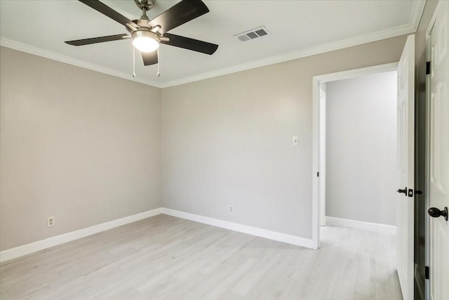 empty room with ornamental molding, visible vents, light wood-style flooring, and baseboards