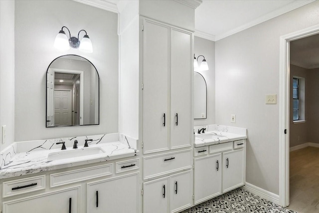 full bath featuring crown molding, two vanities, a sink, and baseboards