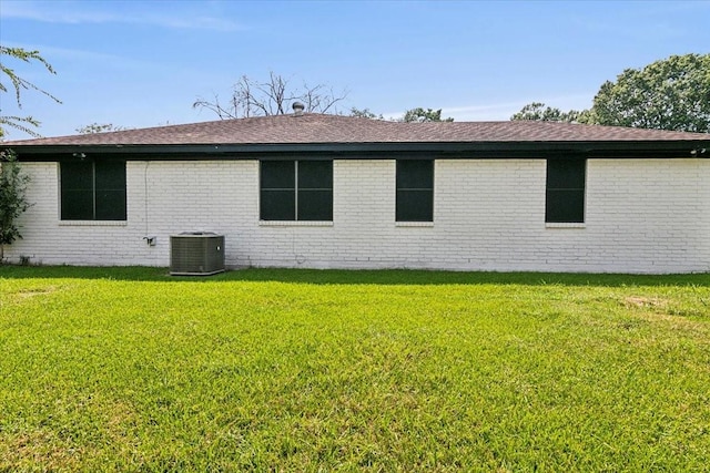 view of side of property with central AC unit, a lawn, and brick siding