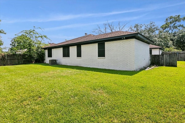 view of home's exterior with central air condition unit, a fenced backyard, a lawn, and brick siding