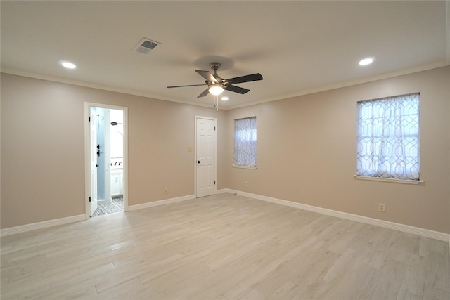 empty room with baseboards, visible vents, crown molding, and light wood finished floors