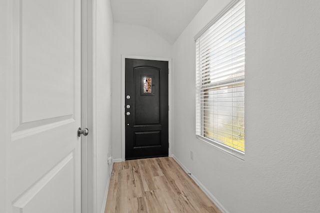 doorway featuring light wood-type flooring and vaulted ceiling