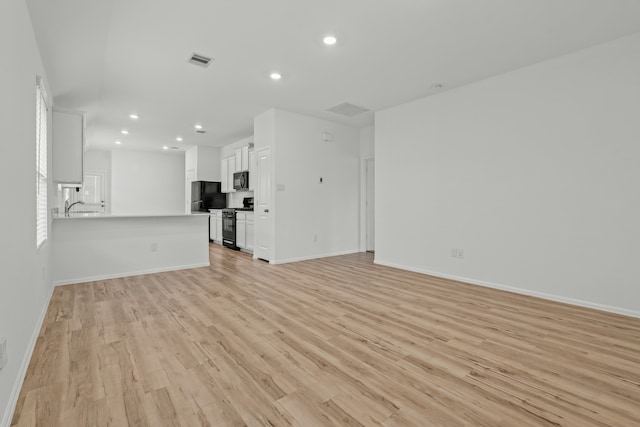 unfurnished living room with light hardwood / wood-style flooring and sink