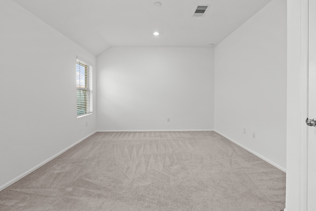 carpeted spare room with vaulted ceiling