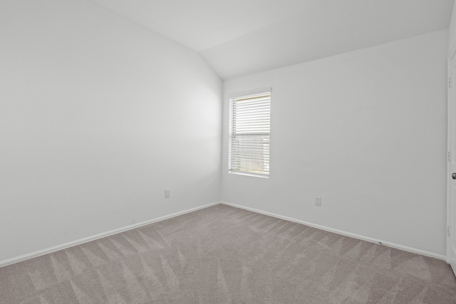 carpeted empty room featuring lofted ceiling