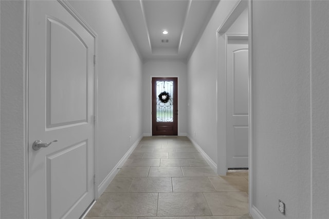 doorway to outside featuring light tile patterned floors and a raised ceiling