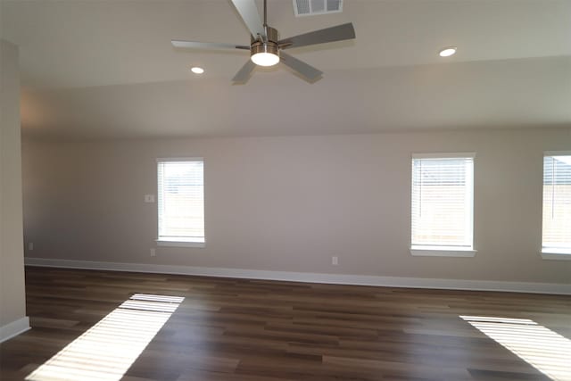 spare room featuring lofted ceiling, plenty of natural light, dark hardwood / wood-style floors, and ceiling fan