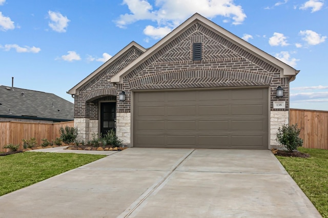 french provincial home featuring an attached garage, stone siding, fence, and brick siding