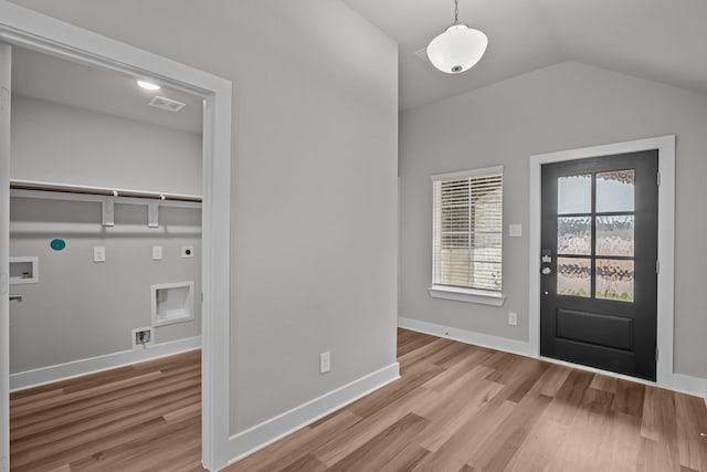 foyer with visible vents, baseboards, vaulted ceiling, and wood finished floors