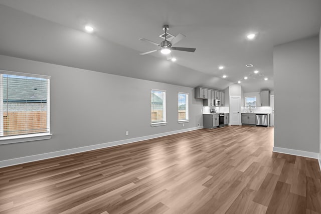 unfurnished living room featuring baseboards, wood finished floors, vaulted ceiling, a sink, and recessed lighting