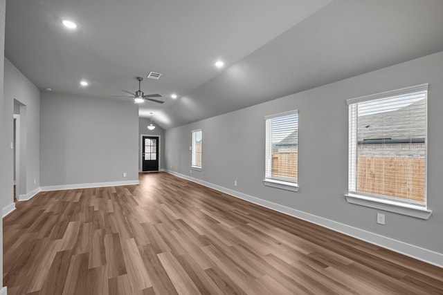 spare room with lofted ceiling, wood finished floors, visible vents, and baseboards