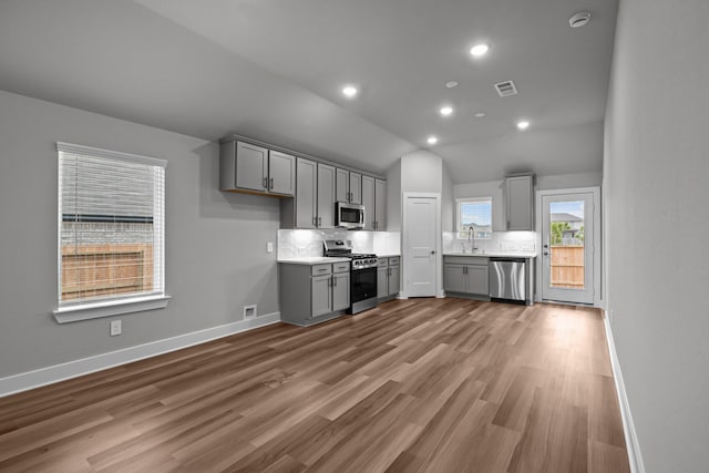 kitchen featuring stainless steel appliances, tasteful backsplash, a sink, and gray cabinetry