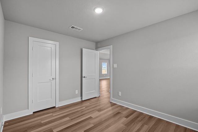 unfurnished bedroom with visible vents, baseboards, and wood finished floors