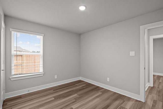 spare room with baseboards and wood finished floors