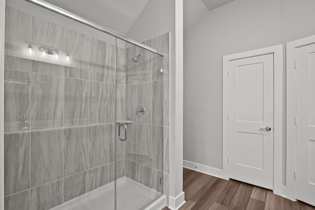 bathroom featuring a stall shower, baseboards, vaulted ceiling, and wood finished floors