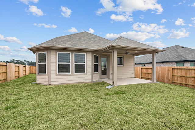 rear view of house with roof with shingles, a lawn, a patio area, ceiling fan, and a fenced backyard